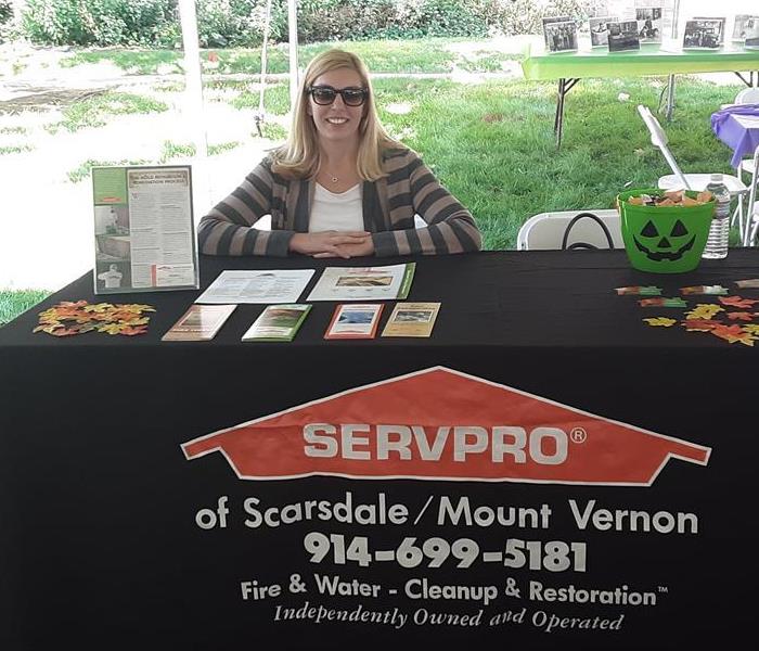 a woman sitting at a black SERVPRO branded booth outdoors 