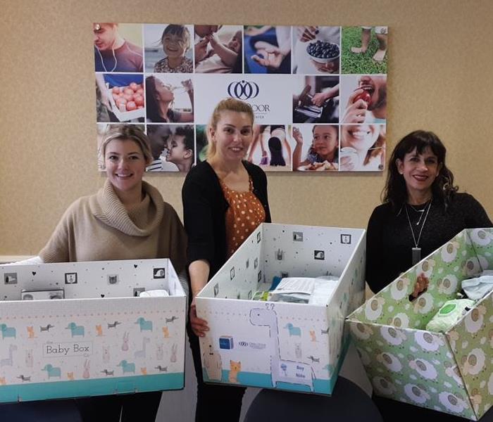 three women holding large boxes full of baby supplies