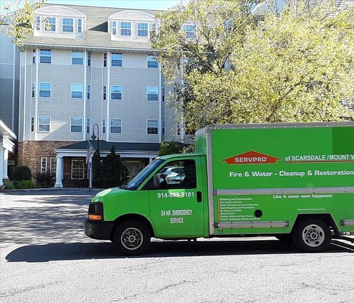 a green SERVPRO truck in front of a commercial building 